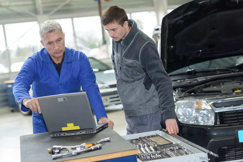auto mechanic teacher and trainee performing tests at mechanic school